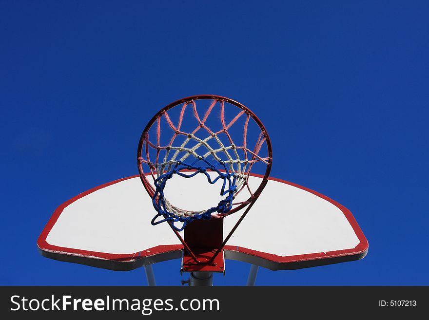 Basketball net, goal and backboard against a blue sky