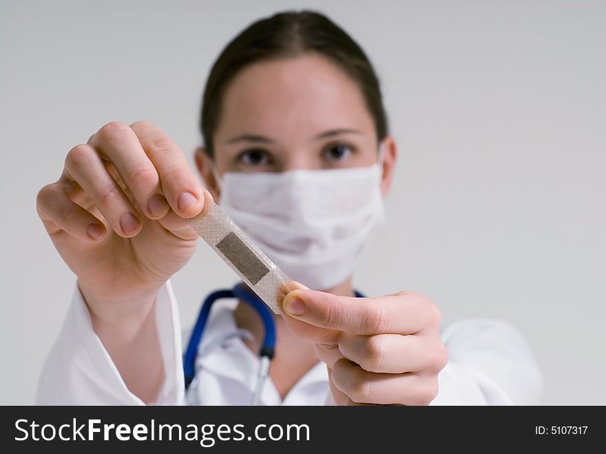 An isolated head shot of a doctor/nurse holding out a bandage, as if to put it on patient. An isolated head shot of a doctor/nurse holding out a bandage, as if to put it on patient.