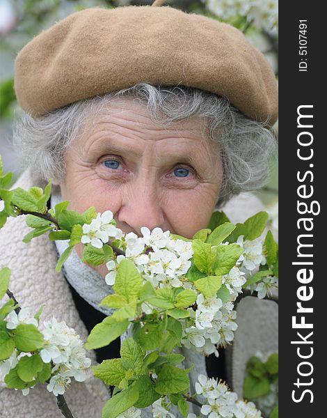 Happy granny smells white flowers in spring garden