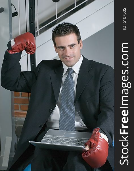 A shot of a businessman, in a suit, wearing a pair of boxing gloves. A shot of a businessman, in a suit, wearing a pair of boxing gloves.