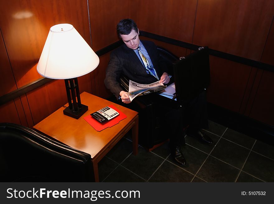 Businessman waiting in an office lobby with his briefcase open. Businessman waiting in an office lobby with his briefcase open
