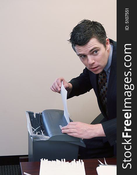 Caucasian businessman furtively shredding documents at his desk. Caucasian businessman furtively shredding documents at his desk