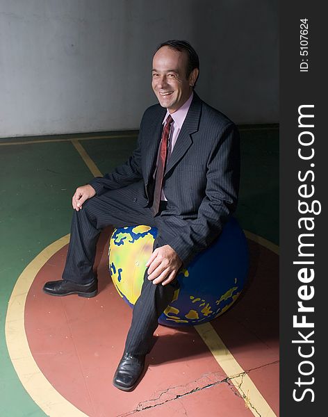 A isolated shot of a businessman sitting on top of a globe. A isolated shot of a businessman sitting on top of a globe.