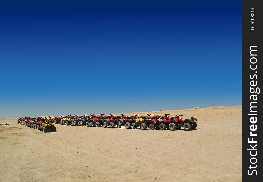 Quad motorcycles in desert over blue sky
