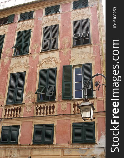 Beautiful old painted house with green shutters in Italian town. Beautiful old painted house with green shutters in Italian town