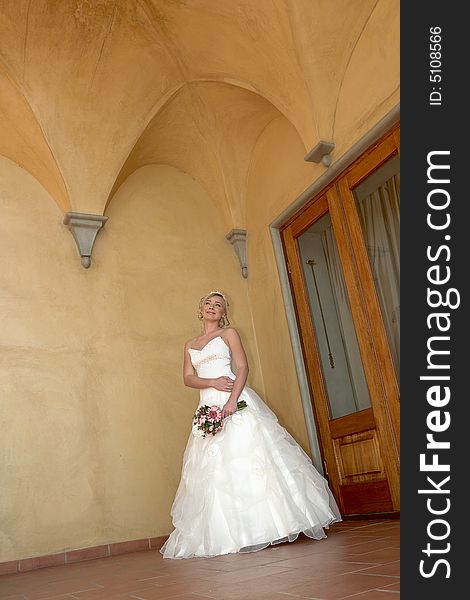 A bride standing under arch in her dress. A bride standing under arch in her dress