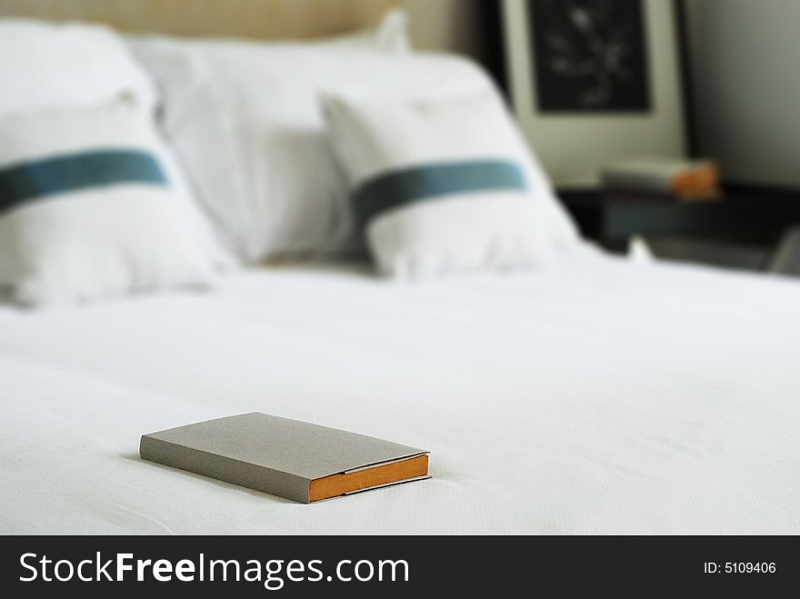 Book on a white, neatly made bed. Book on a white, neatly made bed.