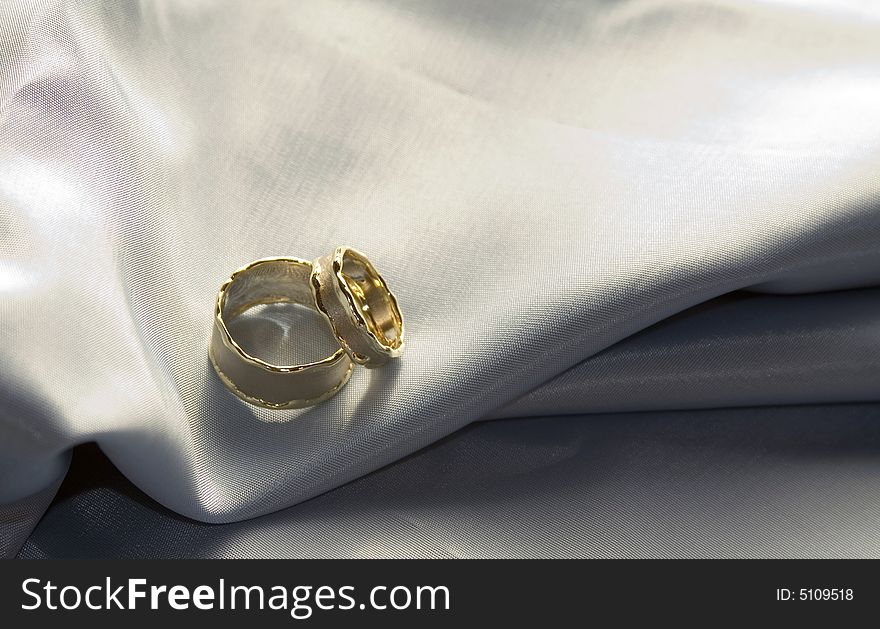 Beautiful unique wedding rings on a silk pillow.
