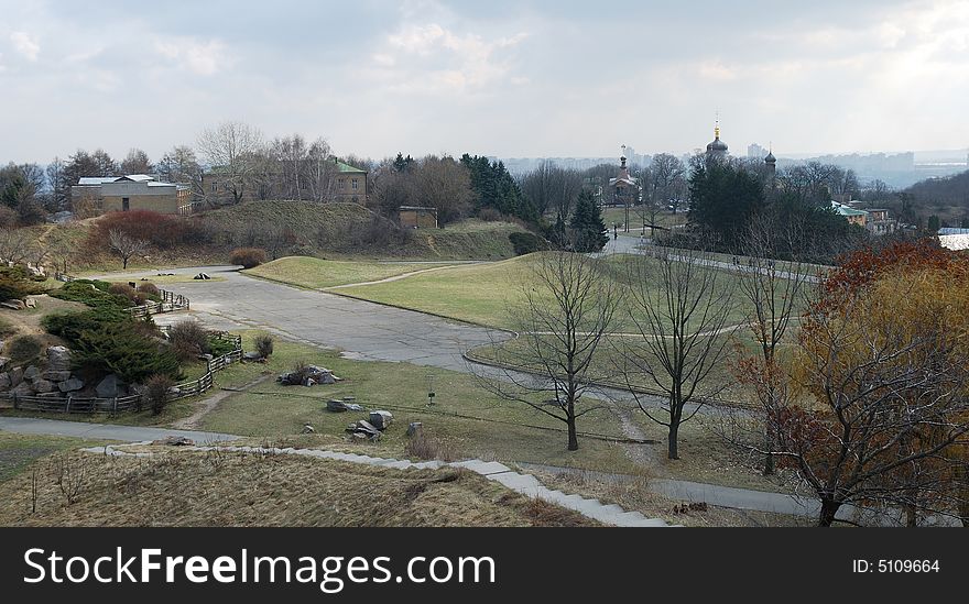 Early spring view down city garden with green lawns, stone hills and curve pathes. Early spring view down city garden with green lawns, stone hills and curve pathes