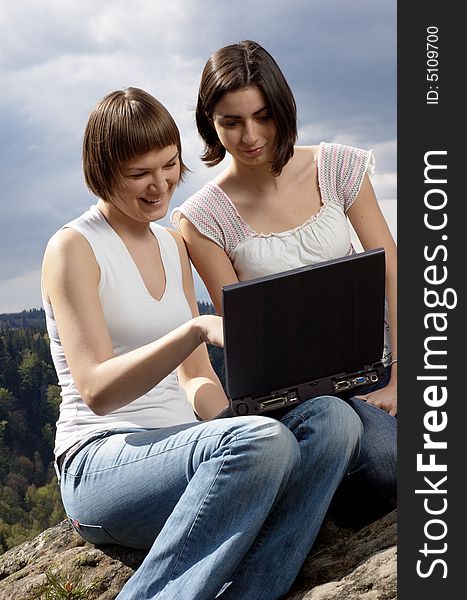 Two friends with laptop on a rock. Two friends with laptop on a rock
