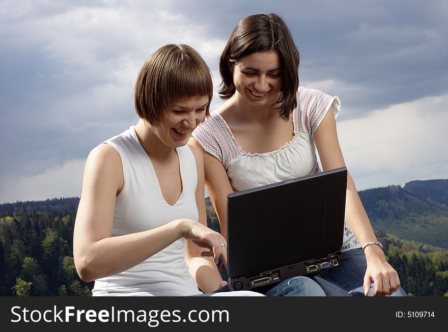 Two friends with laptop on a rock. Two friends with laptop on a rock