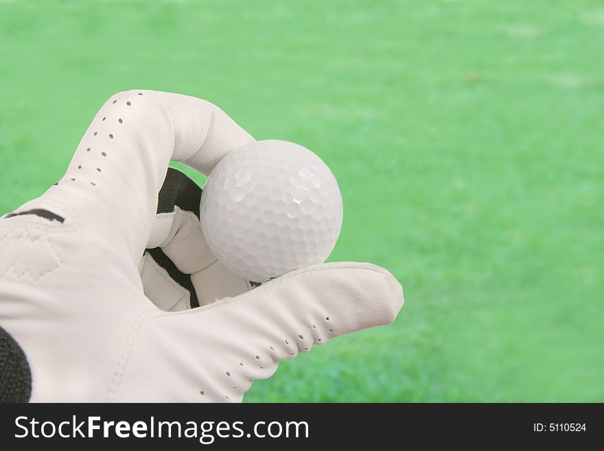 Hand holding a golf ball with a green background