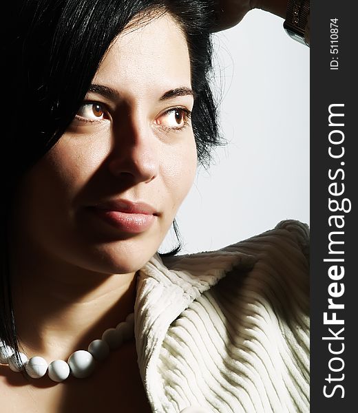 A high-key portrait about an attractive trendy lady with black hair who is looking at something and she has a glamorous look. She is wearing a white coat and a white necklace. A high-key portrait about an attractive trendy lady with black hair who is looking at something and she has a glamorous look. She is wearing a white coat and a white necklace.