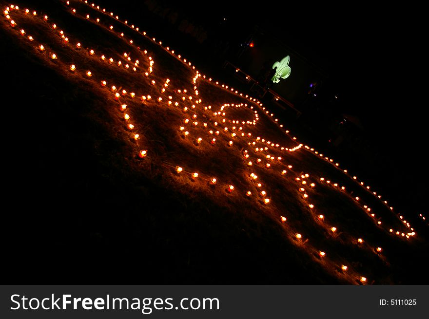 Many lightened candles are standing on the ground at night