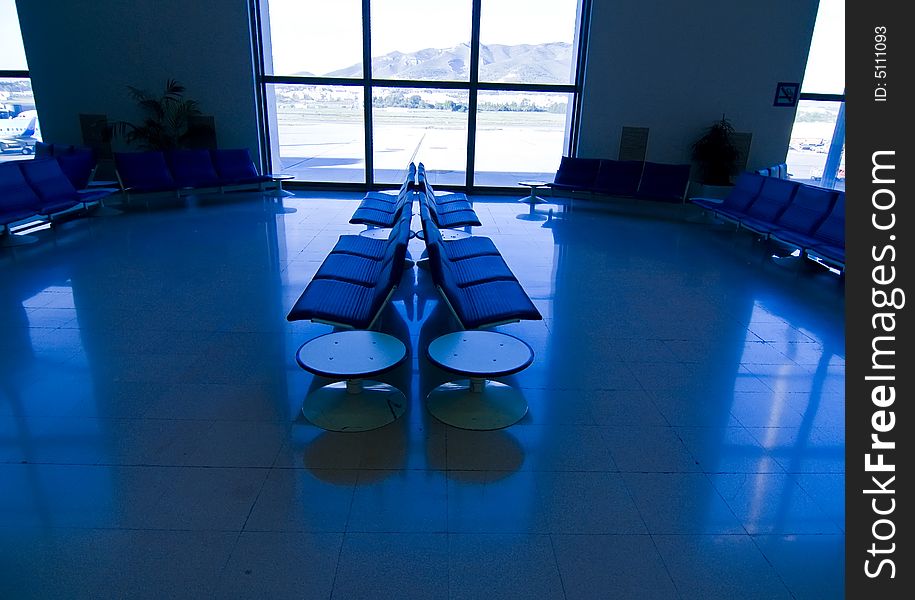 Unoccupied sits at airport, blue toned.