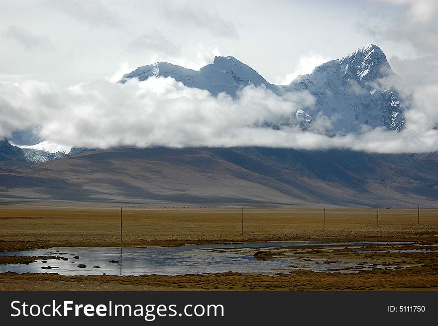 The brook and meadow with power poles at the foot of the snow mountain,Tibet,China. The brook and meadow with power poles at the foot of the snow mountain,Tibet,China.