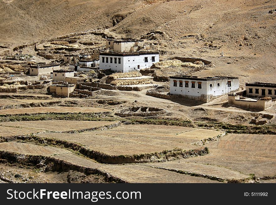 A small Tibetan village of several houses lies by the side of the fallow field. A small Tibetan village of several houses lies by the side of the fallow field.