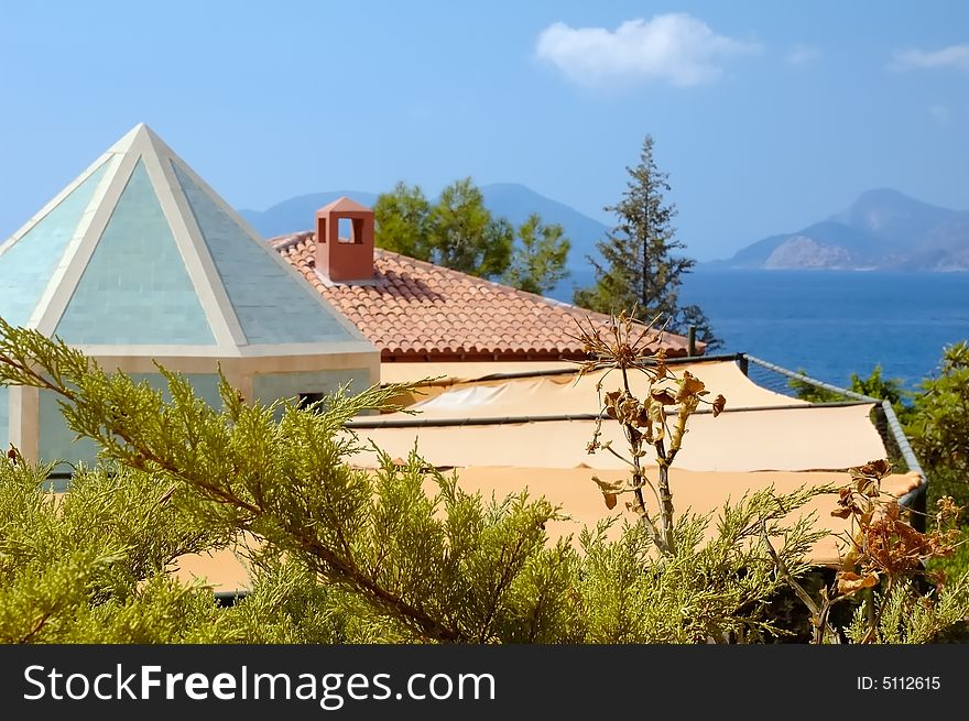 View on sea and mountains over roofs of coastal hotel