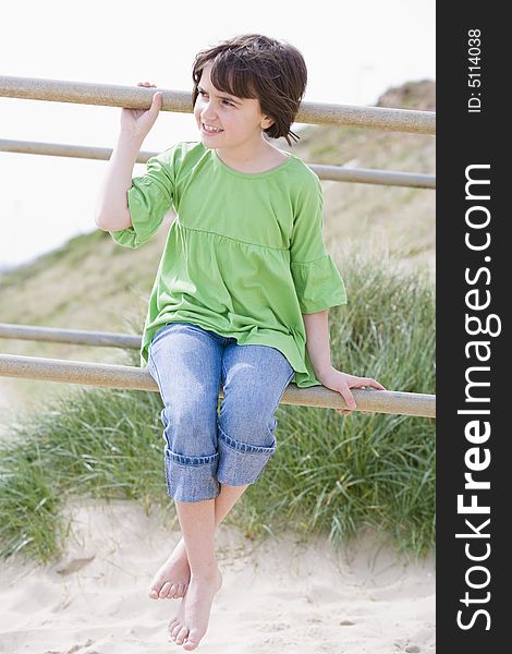 Young child sitting on railings by the beach. Young child sitting on railings by the beach