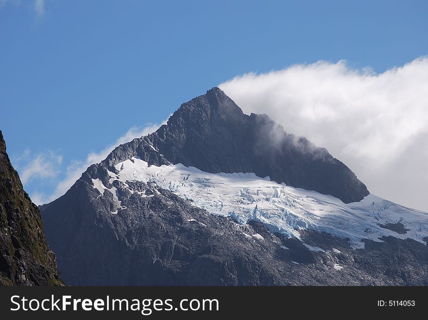 Fog lifts off the peak of mountain in the Fiordland, NZ. Fog lifts off the peak of mountain in the Fiordland, NZ.