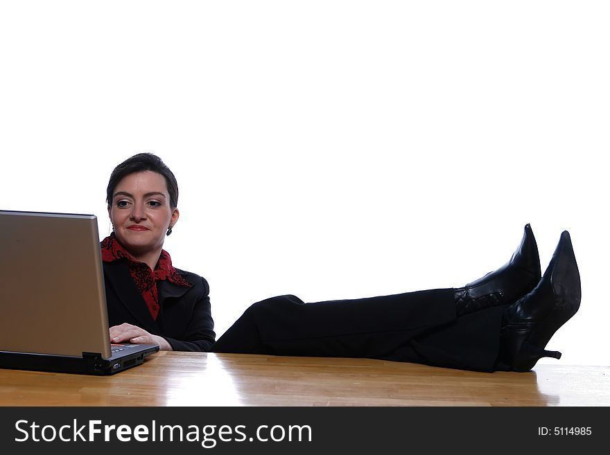 An isolated, on white, shot of a businesswoman working at computer with her legs and feet up on the desk. An isolated, on white, shot of a businesswoman working at computer with her legs and feet up on the desk.