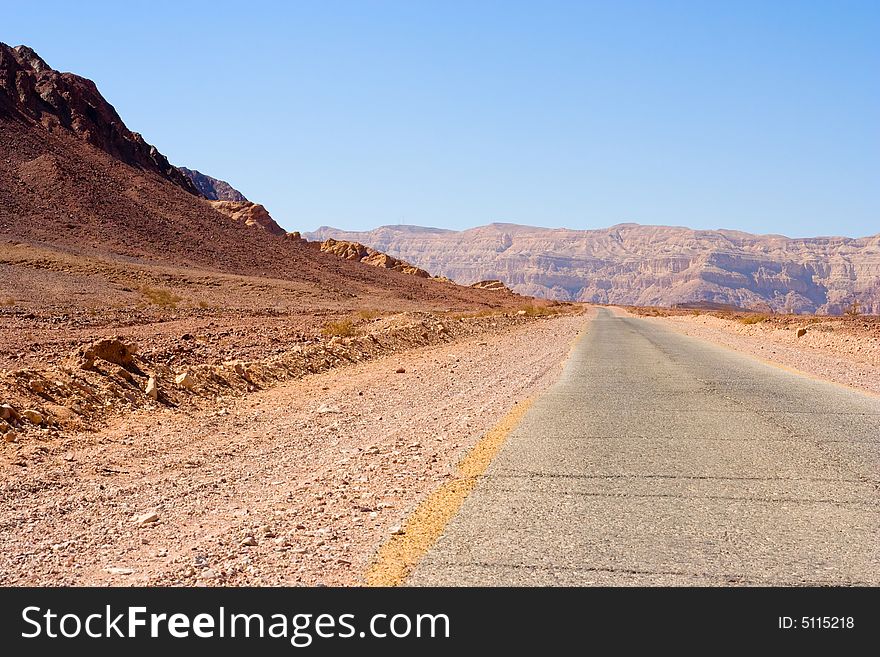 Road in desert toward mountains in the middle of the day. Road in desert toward mountains in the middle of the day