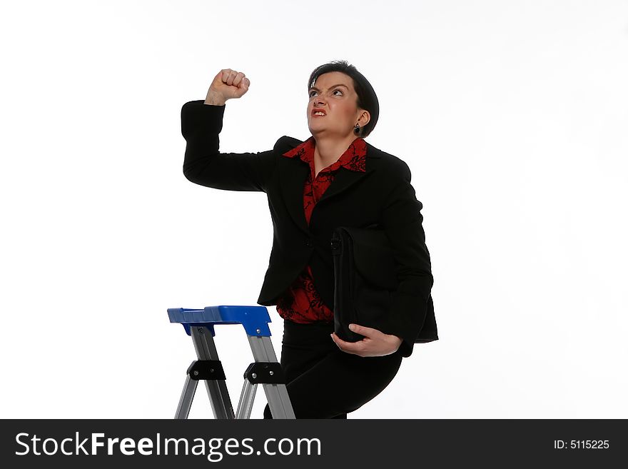 Close-up of an angry businesswoman climbing a stepladder with a determined expression on her face shaking her fist at the ceiling. Close-up of an angry businesswoman climbing a stepladder with a determined expression on her face shaking her fist at the ceiling