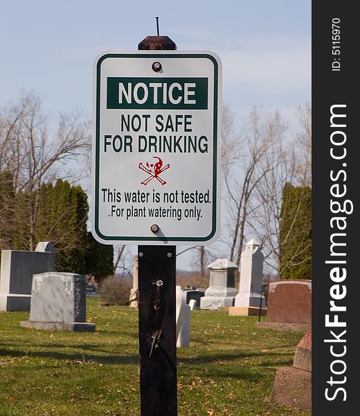 Warning sign about hazardous water posted in a cemetery. Warning sign about hazardous water posted in a cemetery
