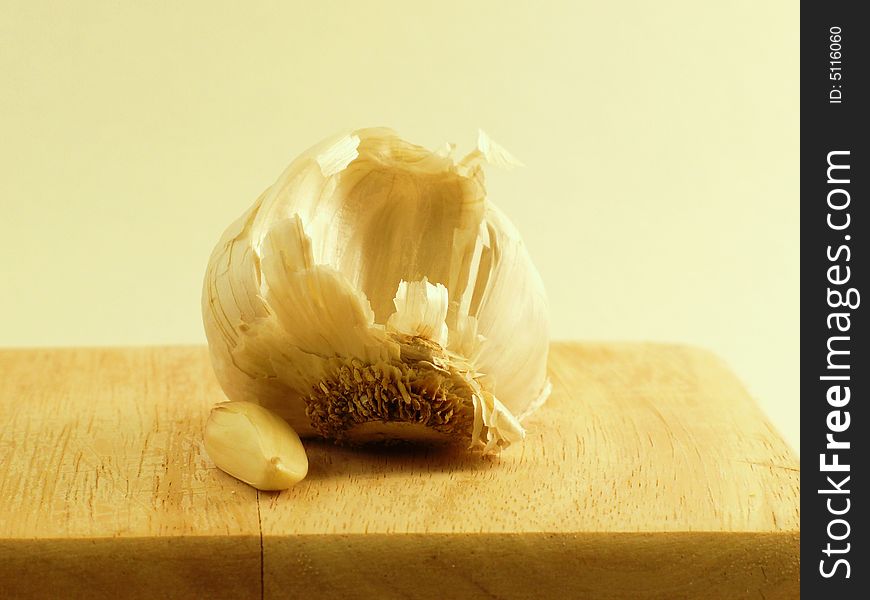 Garlic head and clove on wooden cutting board. Garlic head and clove on wooden cutting board