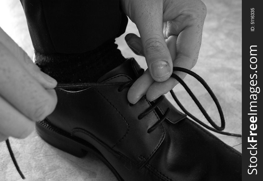 A man doing up his shoe laces. A man doing up his shoe laces