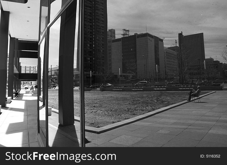 Reflection of a lone man sitting in a park reading a newspaper. Reflection of a lone man sitting in a park reading a newspaper