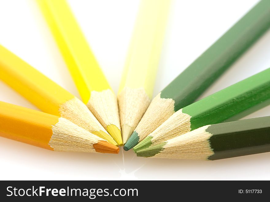 Variously tinted yellow and green pencils on a white background. Variously tinted yellow and green pencils on a white background