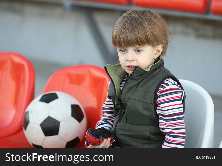 The boy with a toy on empty tribunes of stadium. The boy with a toy on empty tribunes of stadium