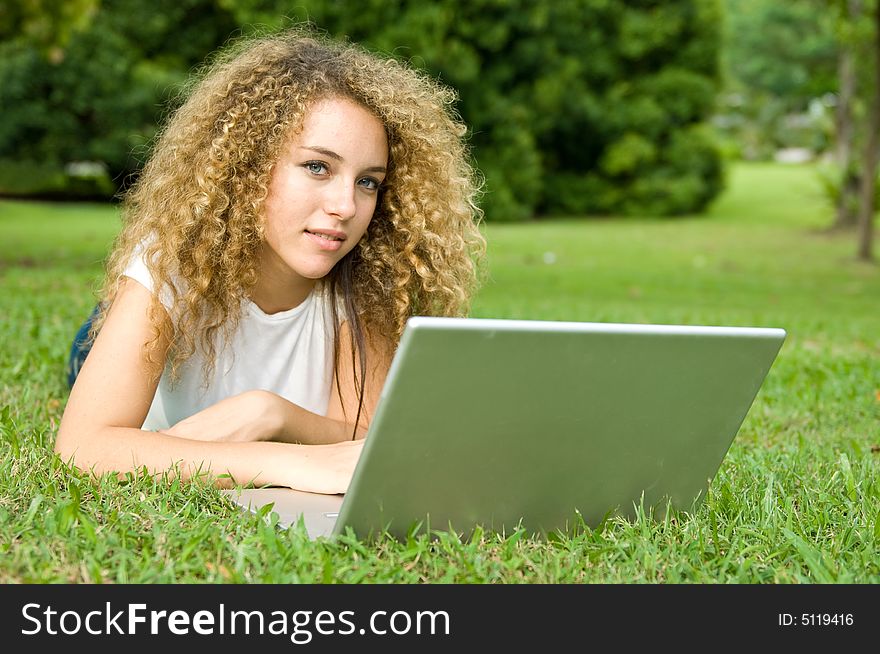 A beautiful young woman using a portable computer outside. A beautiful young woman using a portable computer outside