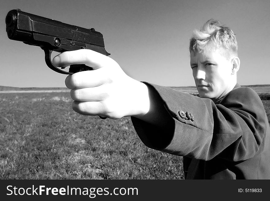 A young man standing with a gun in the middle of a field. A young man standing with a gun in the middle of a field.