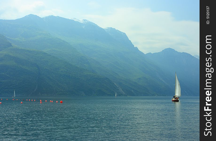 Sailboat on Garda lake early hazy morning