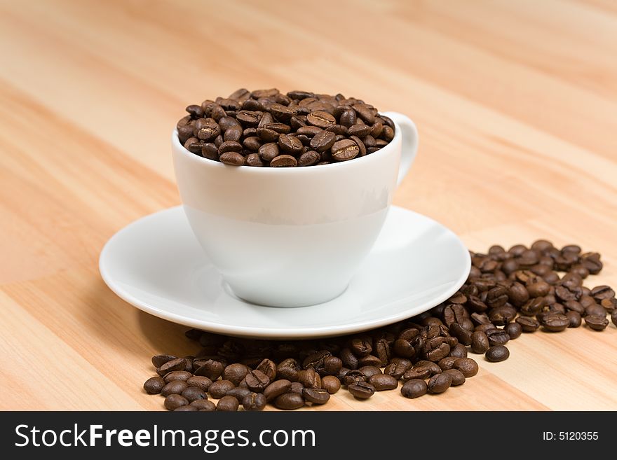 Cup with coffee beans on hardwood floor