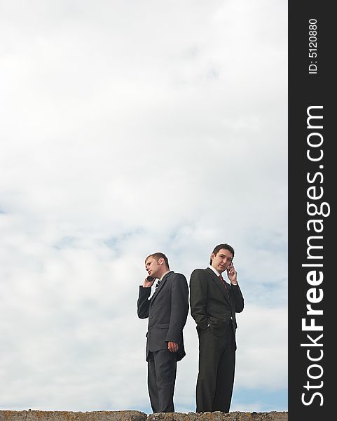 Businessmen talking by phone under the skies