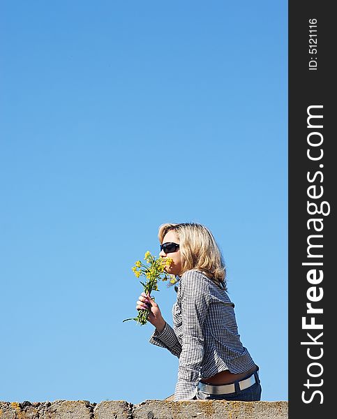 Girl sniffing flowers under the sky