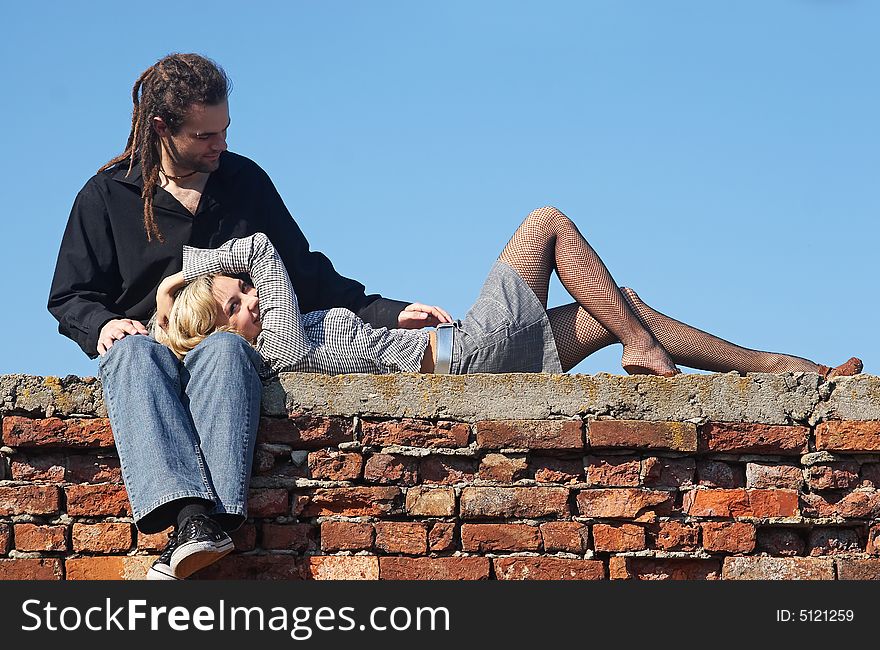 Woman resting on man knees under the sky