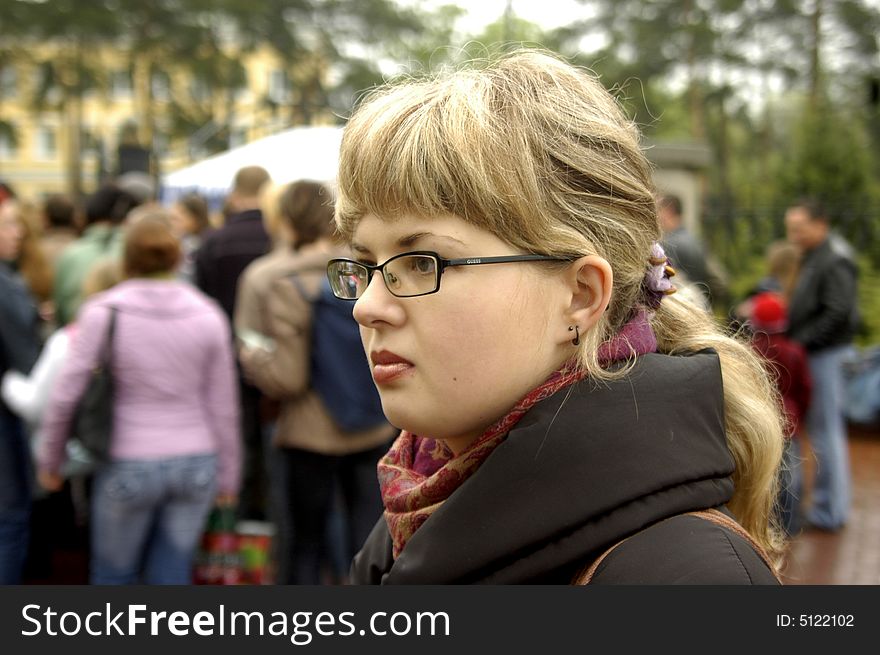 Close-ups portrait of caucasian girl. Crowd is out of focus.