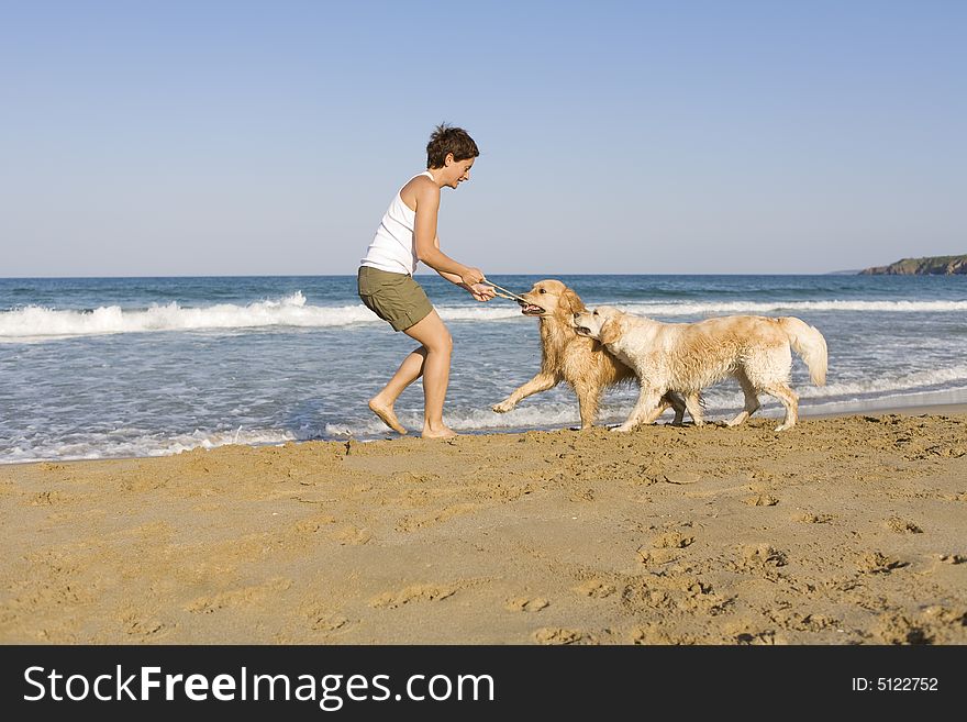 Yong girl playing with her dogs on the beach