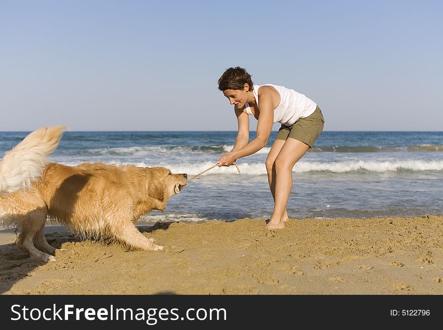 Yong girl playing with her dog on the beach