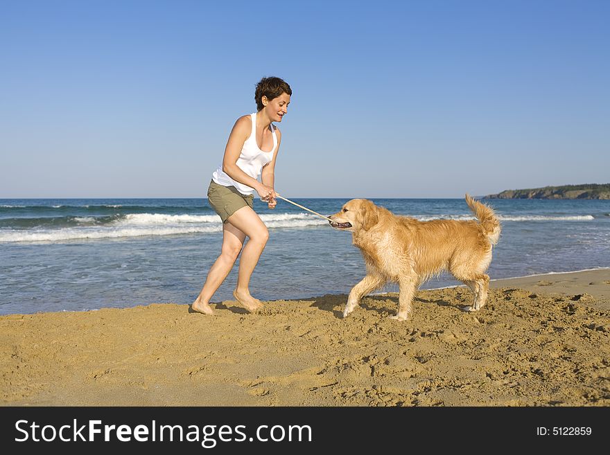 Yong girl playing with her dog on the beach
