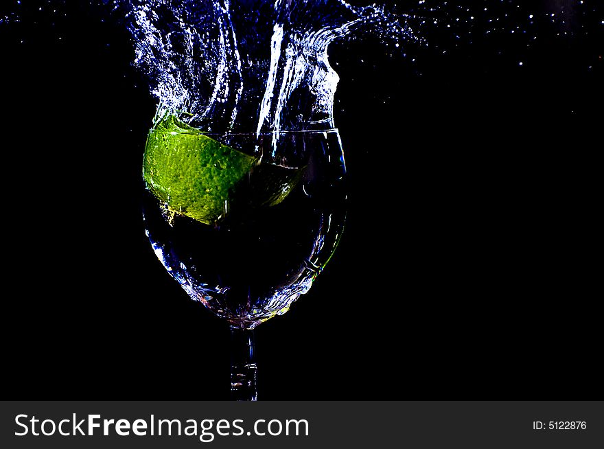 A peace of lemon falling in a glas with water. A peace of lemon falling in a glas with water