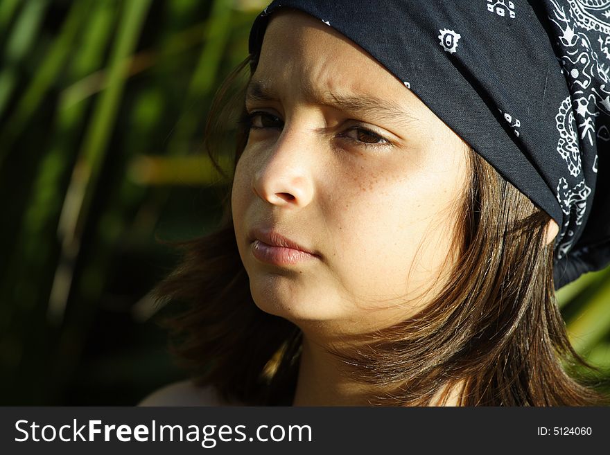 Young boy wearing a bandanna and greenery in the background. Young boy wearing a bandanna and greenery in the background.