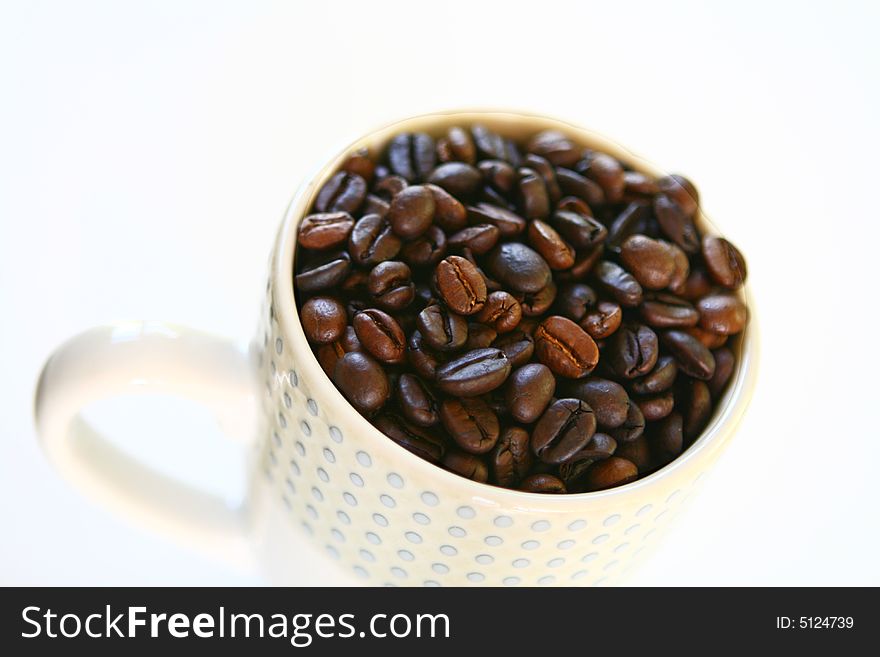 A mug filled with whole bean coffee. A mug filled with whole bean coffee