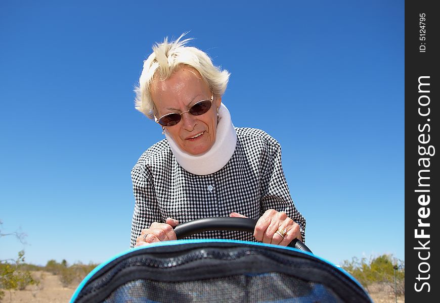 An isolated shot of a grandmother, wearing whiplash neck-brace, pushing a baby stroller. An isolated shot of a grandmother, wearing whiplash neck-brace, pushing a baby stroller.