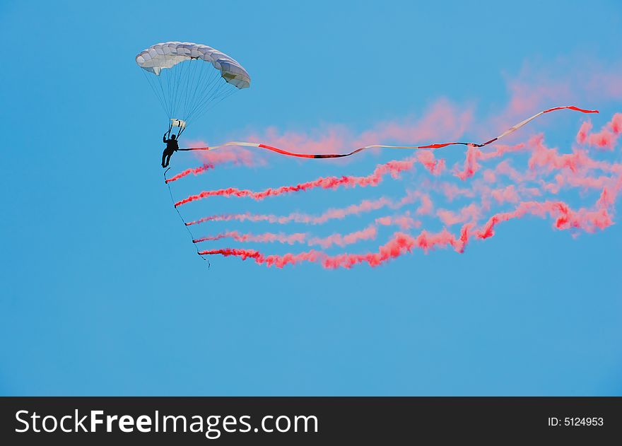 Skydiver with trailing pendant and smoke in red, white and blue. Skydiver with trailing pendant and smoke in red, white and blue