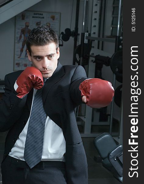 A shot of a businessman, in a gym, wearing boxing gloves. A shot of a businessman, in a gym, wearing boxing gloves.